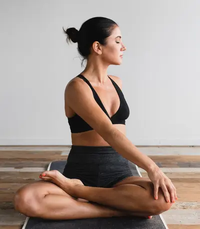 Woman sitting cross-legged in a quiet meditation pose, eyes closed