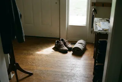 Walking shoes and a rolled sweater by the front door in morning light