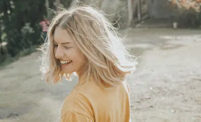 Woman laughing outdoors with her hair blowing in the breeze