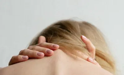 Close-up of a hand resting gently on a person's shoulder and neck